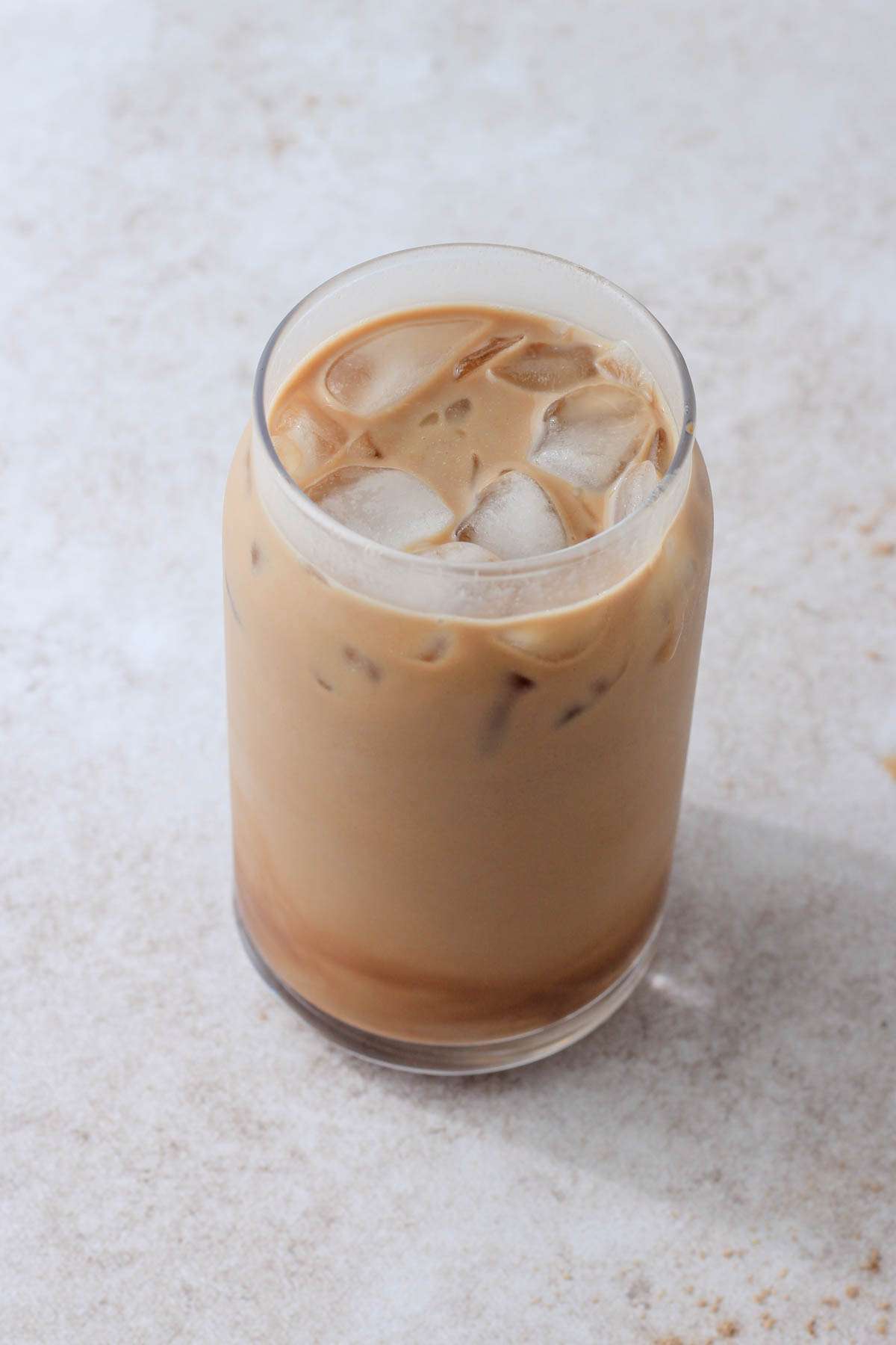 A top down of a tall glass with ice and a vegan chocolate protein almond milk shaken espresso.