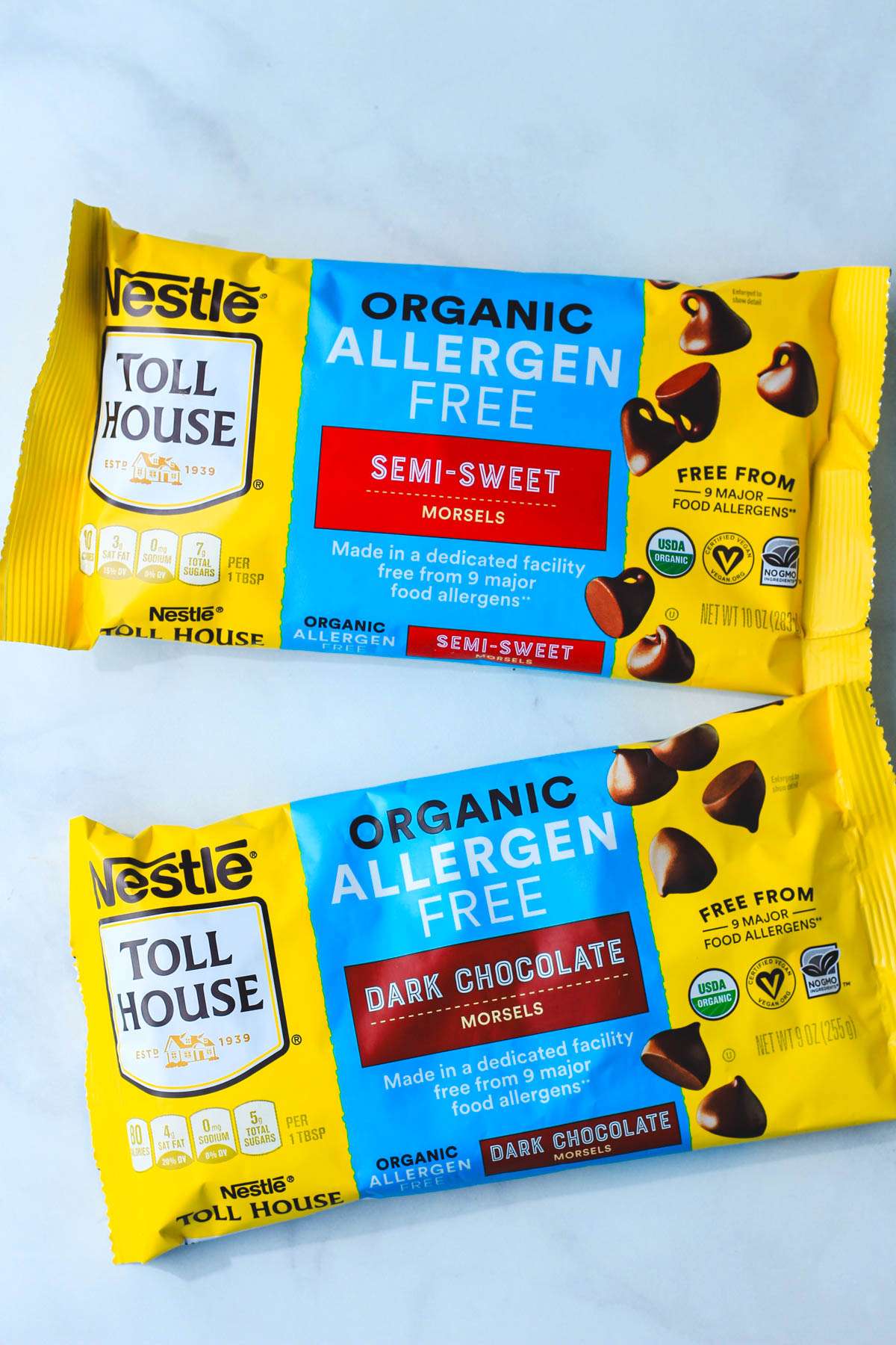 Two bags of Nestle Toll House dairy-free chocolate chips on a grey counter.