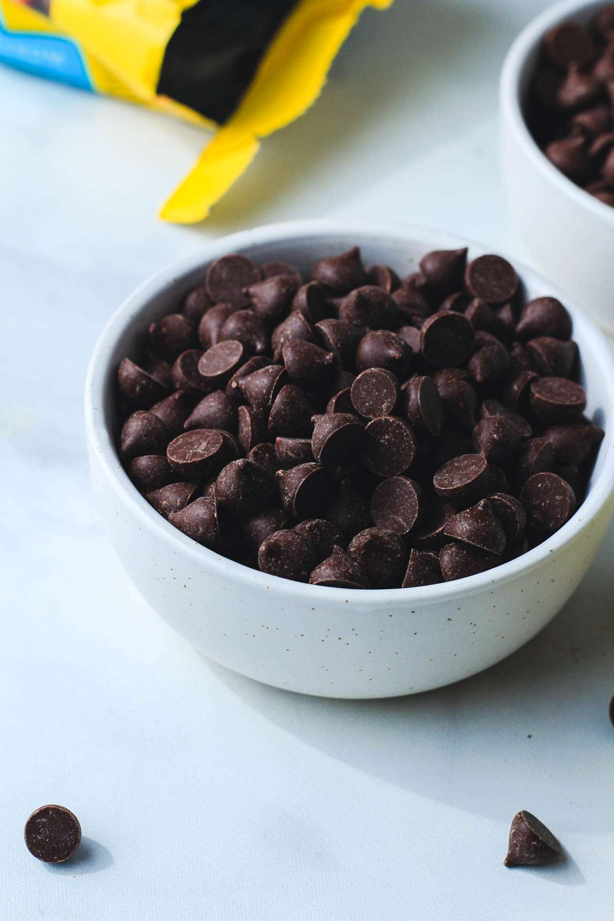 A white bowl with a mound of dairy-free Nestle Toll House chocolate chips on a grey counter.