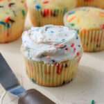 A cream counter with a dairy-free funfetti cupcake topped with funfetti icing.