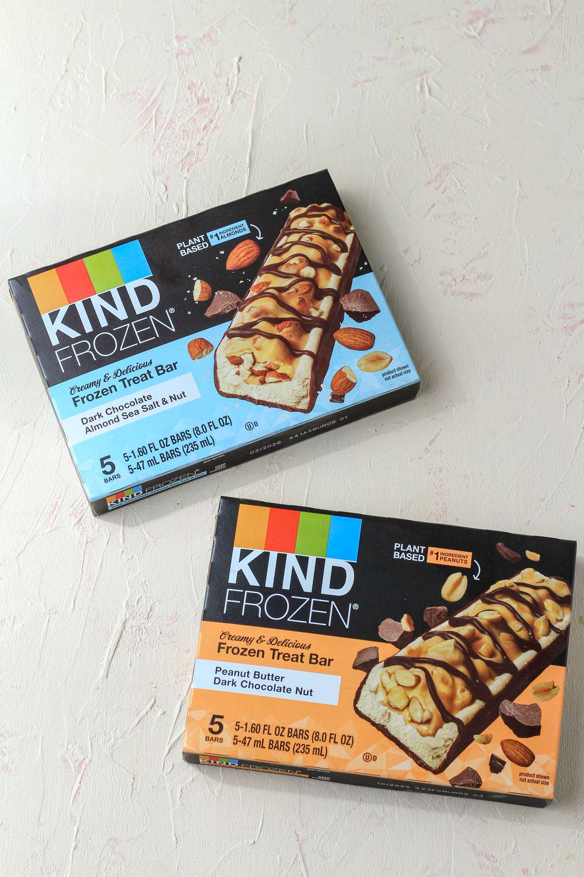 Two boxed of Kind Frozen bars on a cream counter.