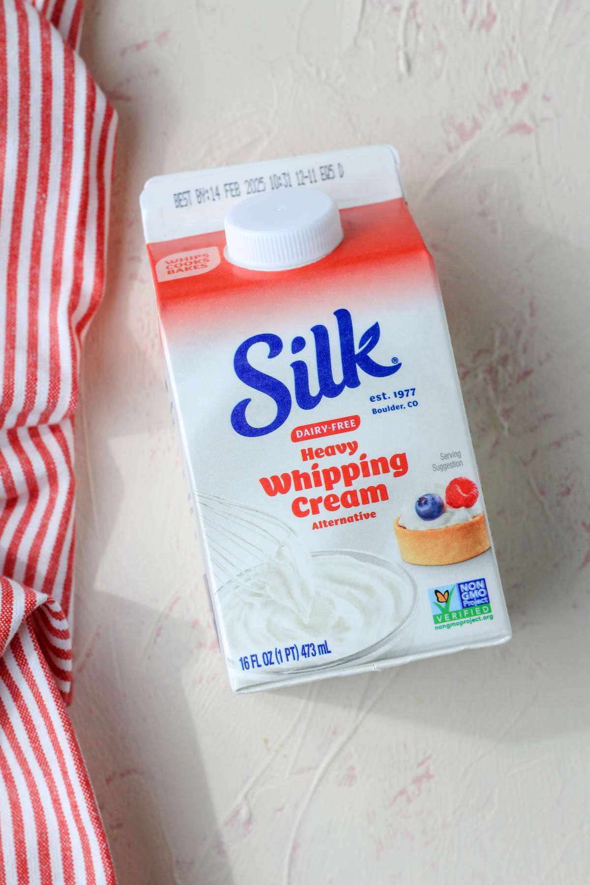 A carton of silk dairy-free heavy whipping cream alternative on a cream and pink counter.