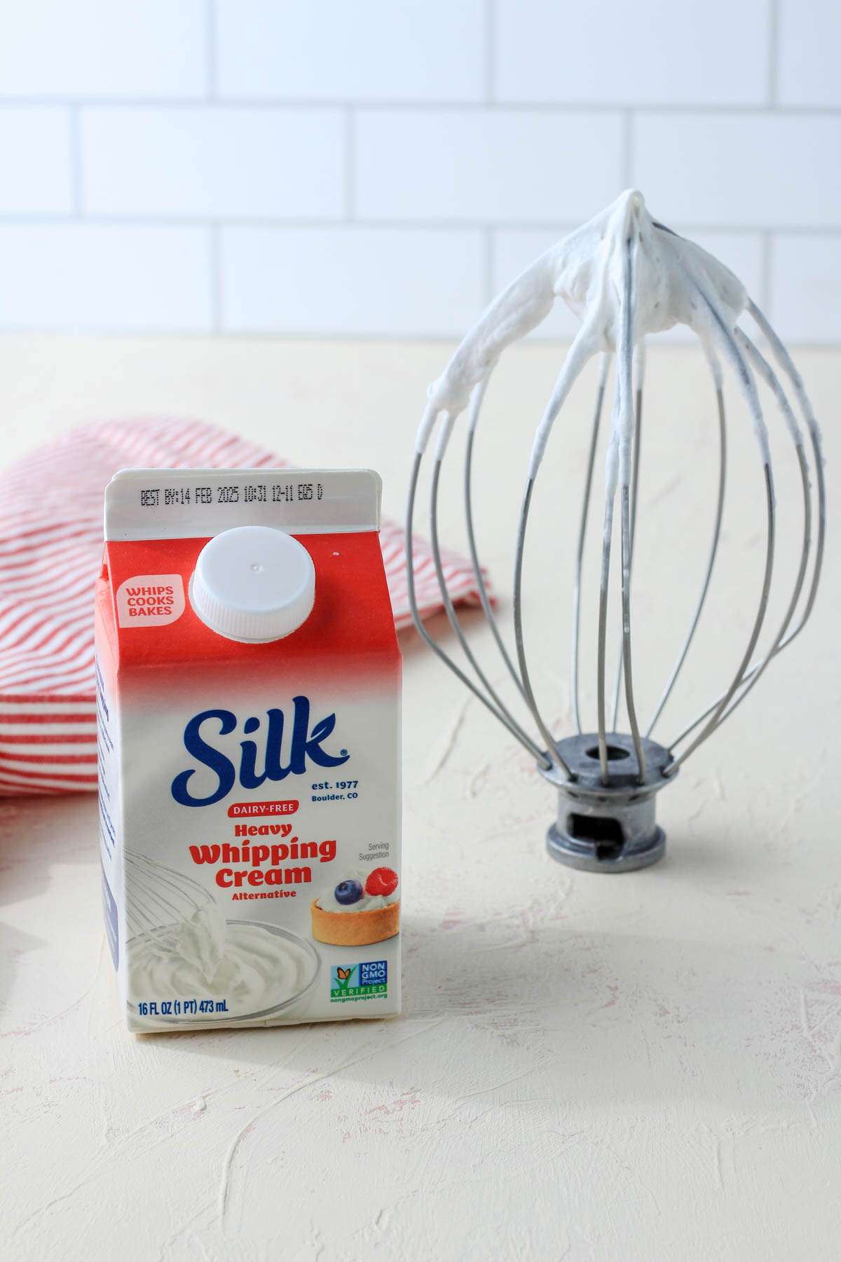 A cream counter with a carton of silk dairy-free heavy whipping cream alternative with a whisk attachment to the right of the carton.