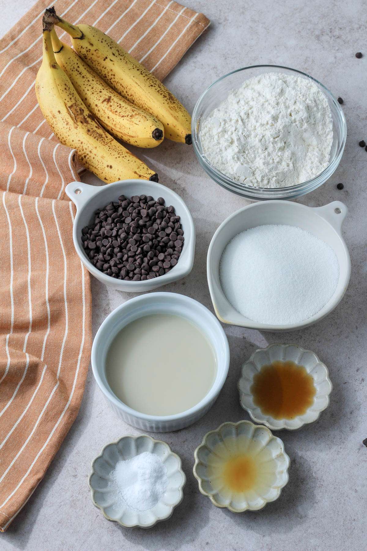 Ingredients for vegan chocolate chip banana bread on a cream counter.