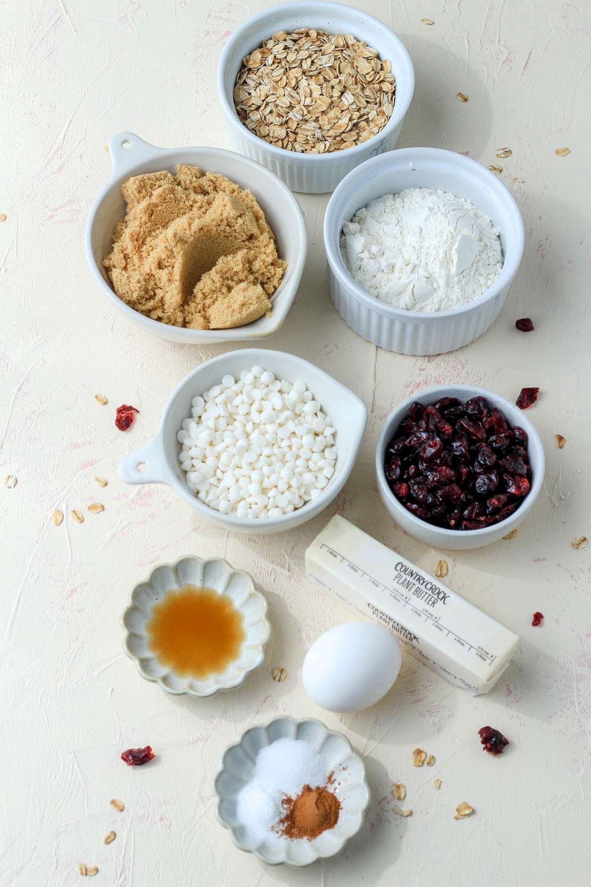 Ingredients for white chocolate and craisin oatmeal cookies on a cream counter.