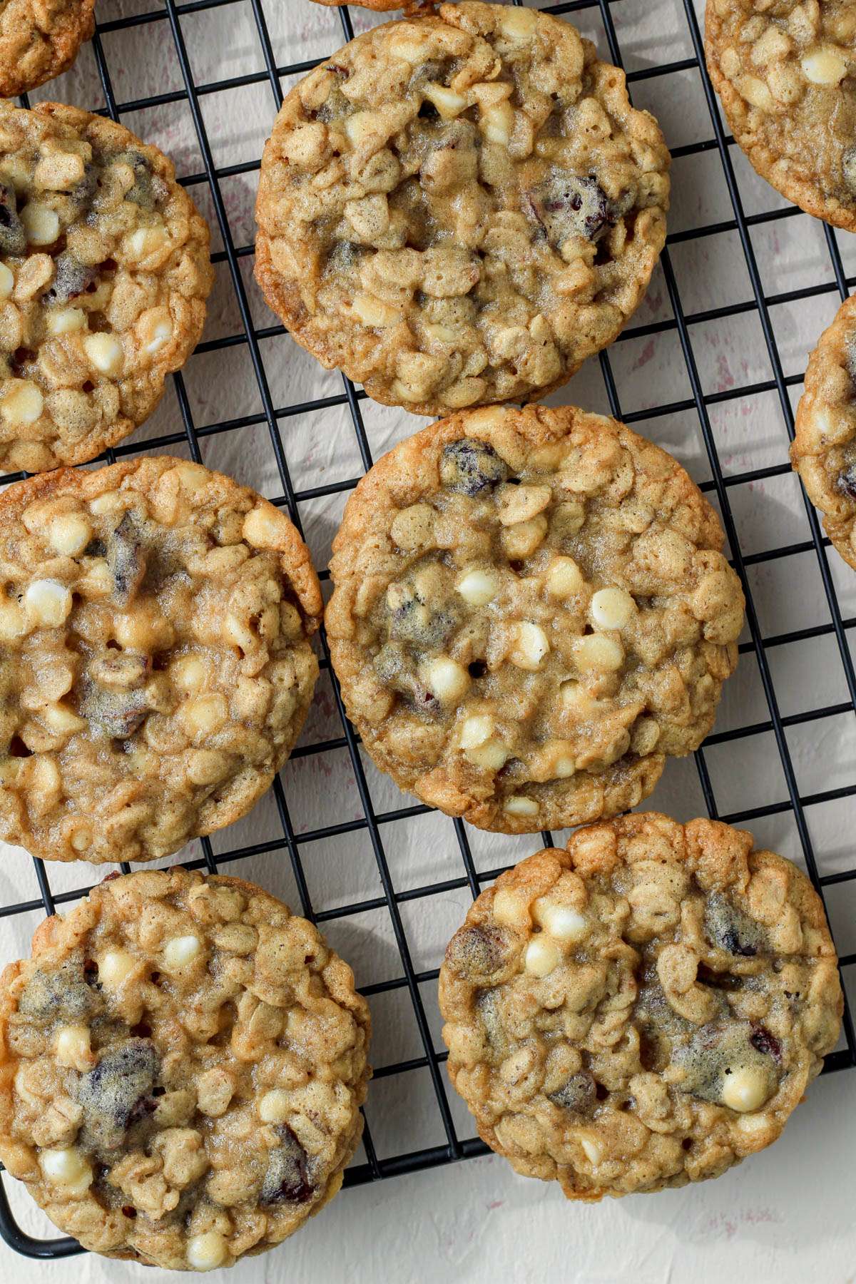 A black cooling rack with white chocolate craisin oatmeal cookies cooling.