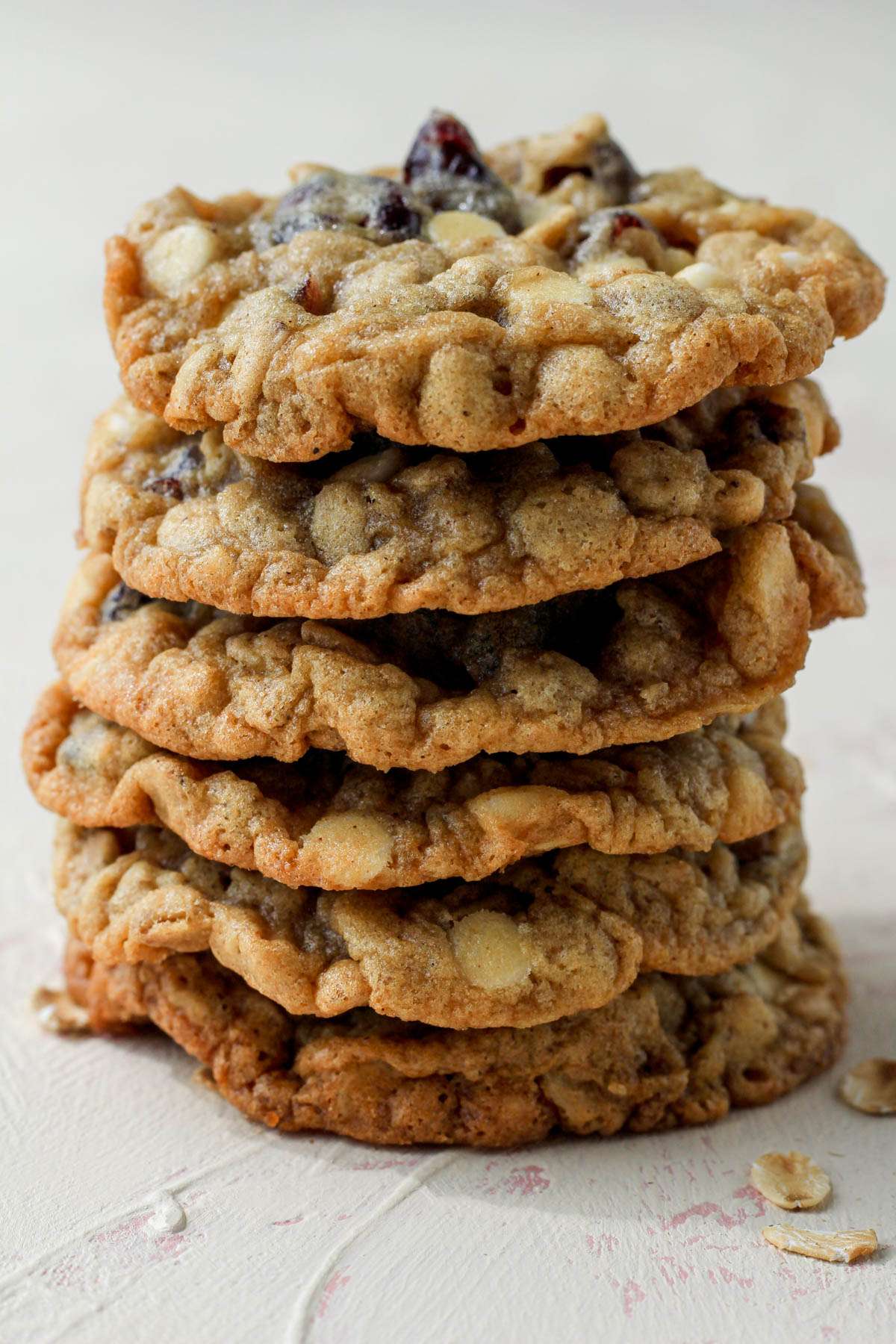 A cream counter with a stack of six oatmeal cookies with white chocolate chips and craisins.