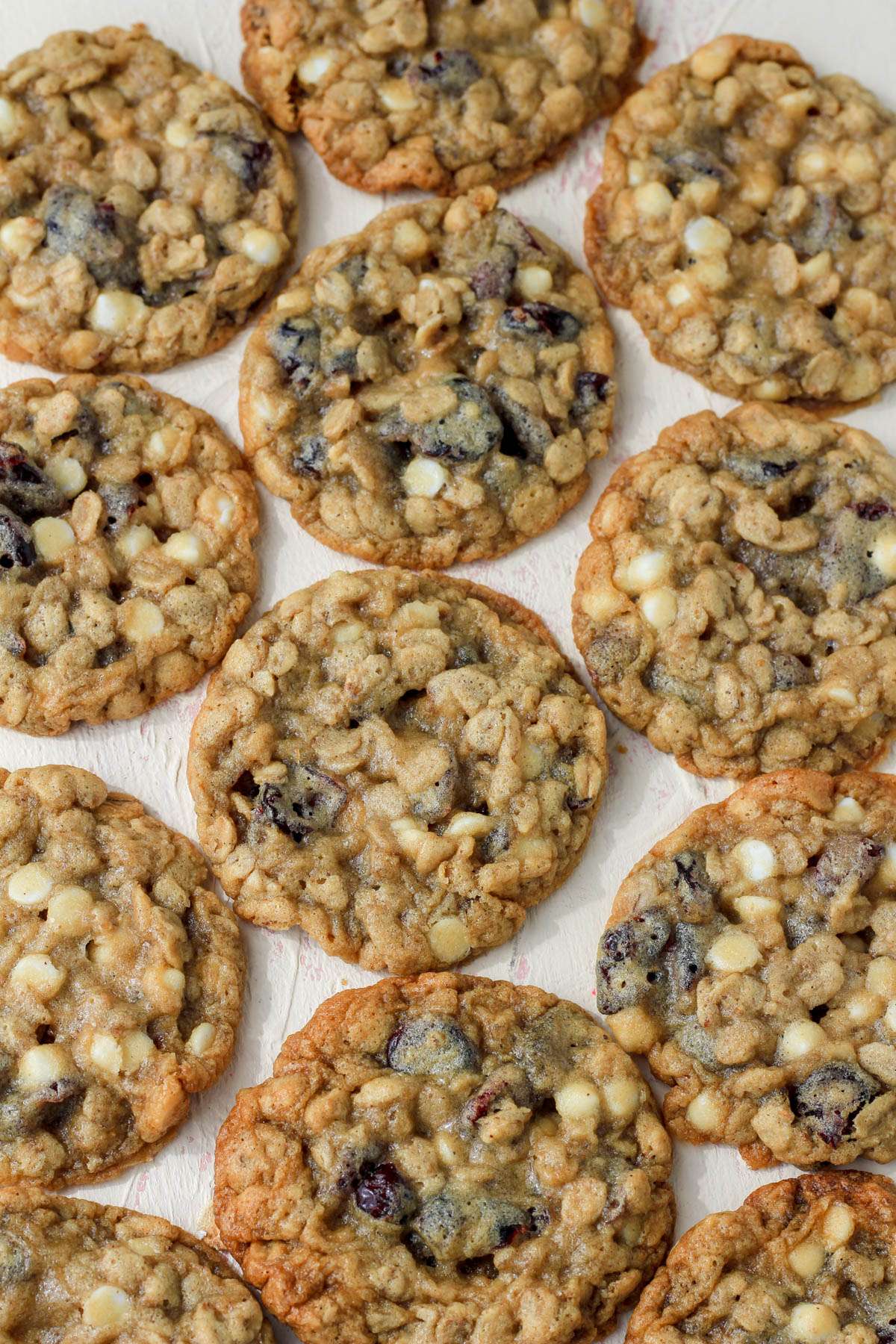 A cream counter with white chocolate and craisin oatmeal cookies lined up on the counter.