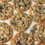 A close up of white chocolate craisin oatmeal cookies on a cream counter.