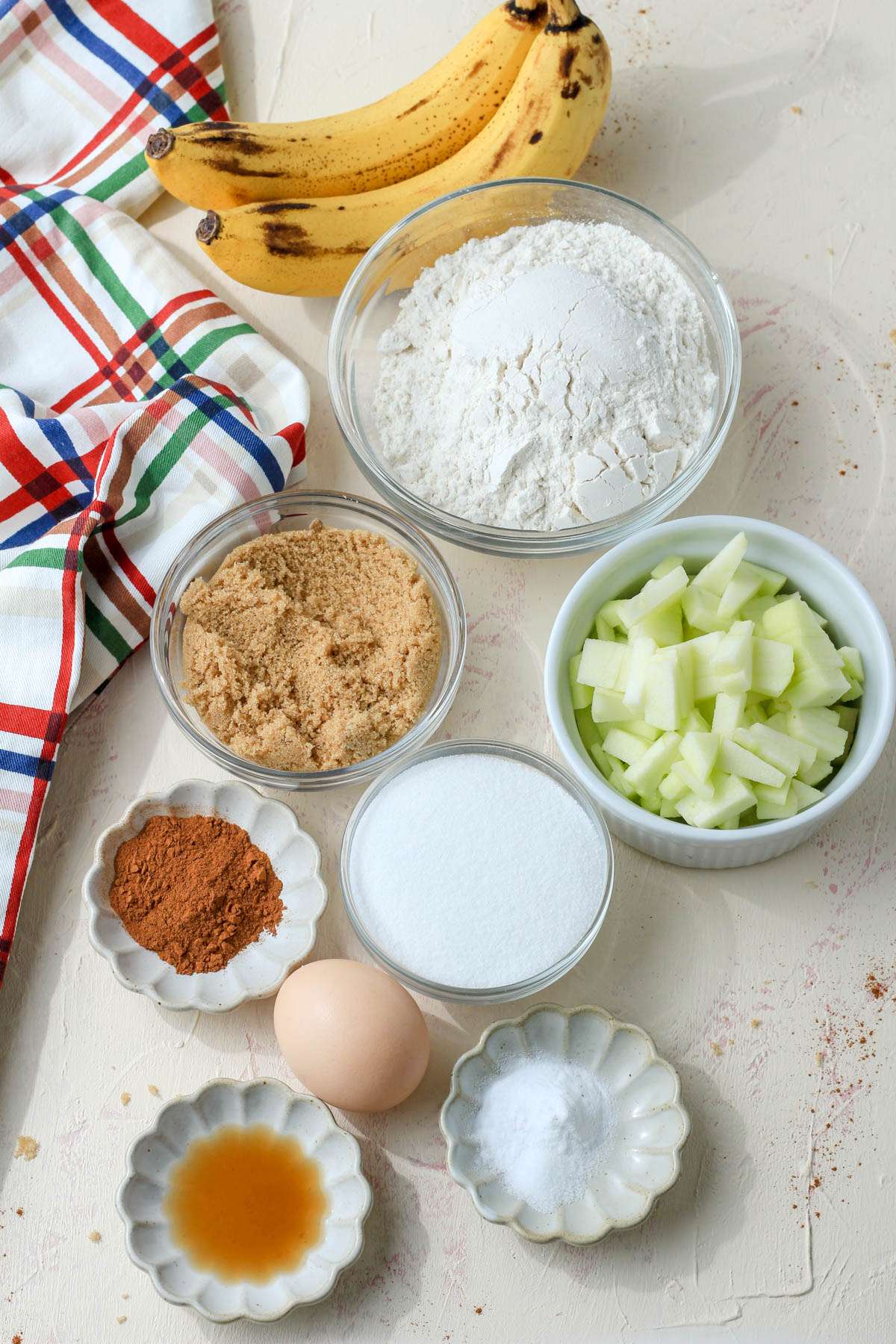 Ingredients for cinnamon apple banana bread on a tan counter.