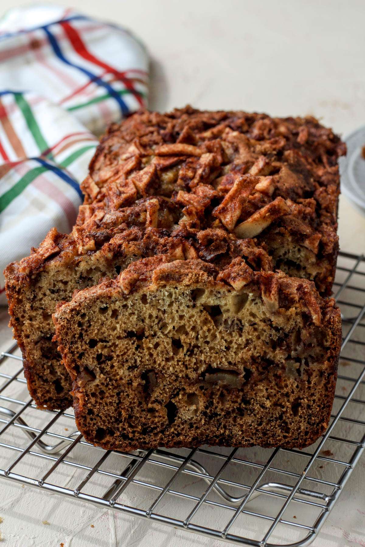 A silver cooling rack on a cream counter with a line of cinnamon apple banana bread.