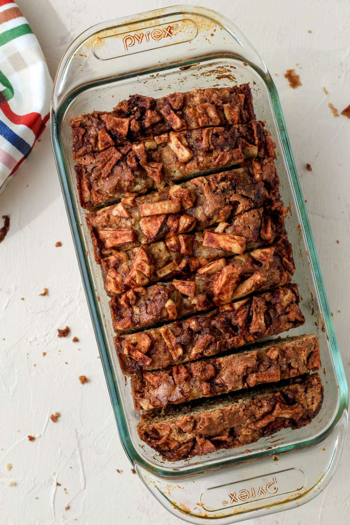 A glass loaf pan filled with one inch thick sliced pieces of cinnamon apple banana bread.