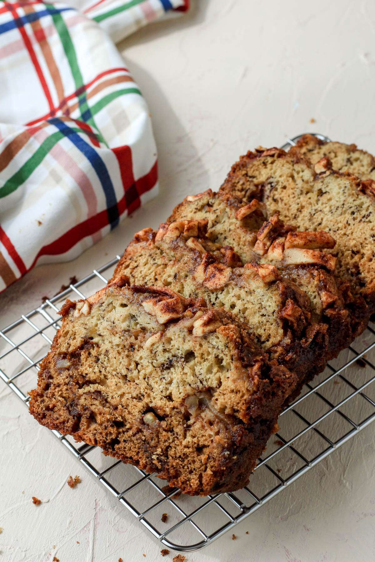 Five slices of cinnamon apple banana bread laying on a silver cooling rack facing the left side.