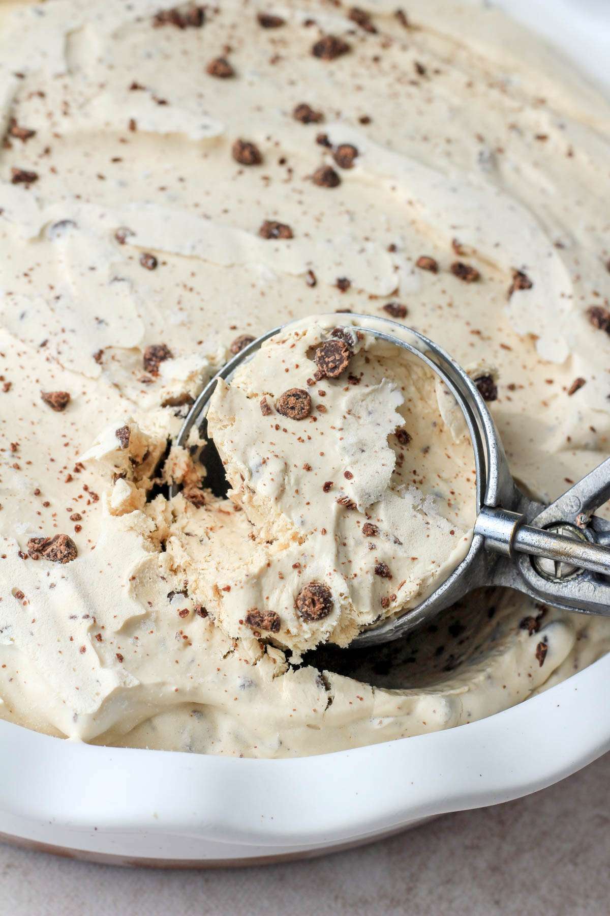 A close up of an ice cream scoop with a small scoop of vegan coffee chip ice cream.