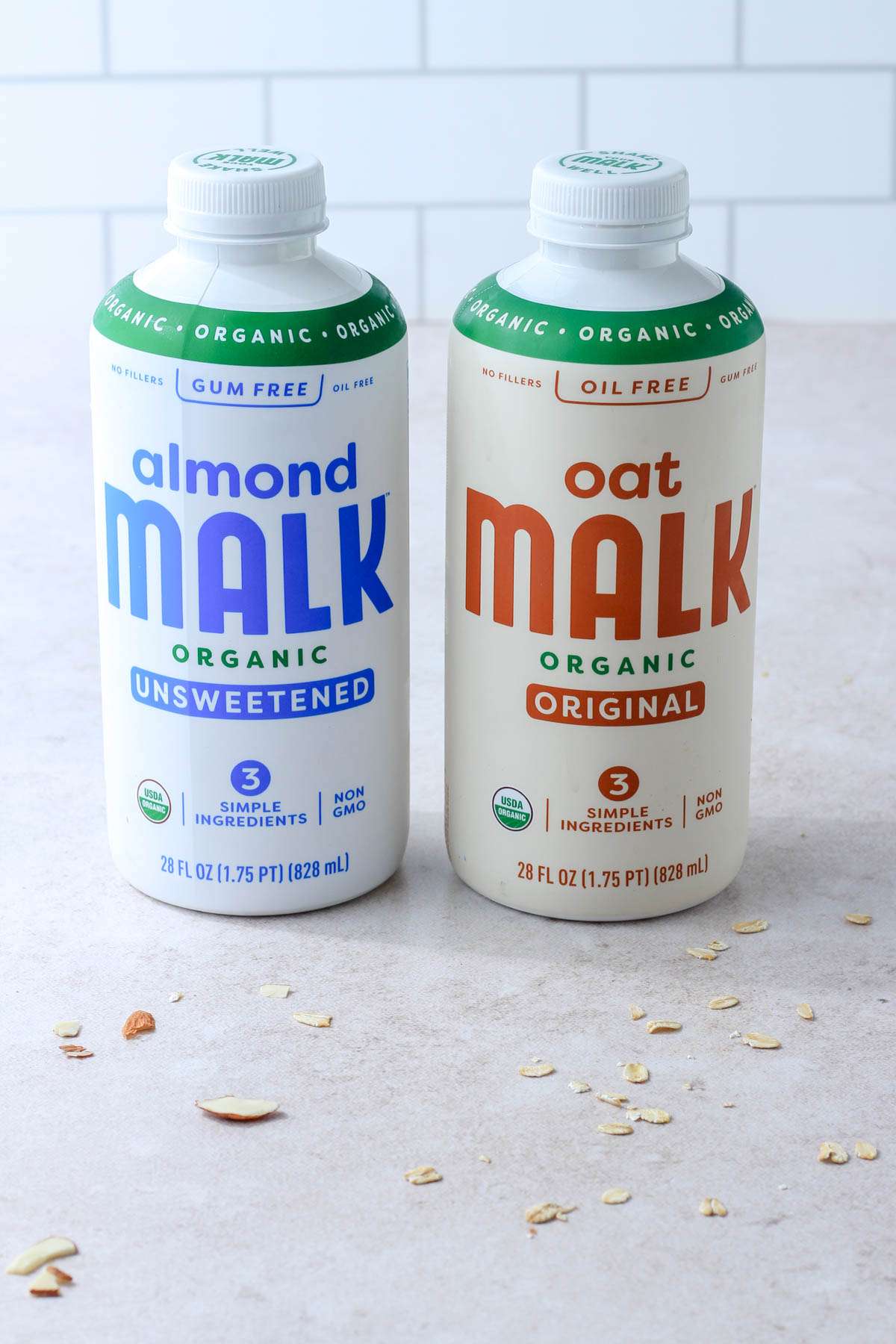 A bottle of almond malk on the left and oat malk on the right on a cream counter.
