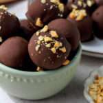 A close up of a small green bowl filled with dairy-free peanut butter oreo truffles.
