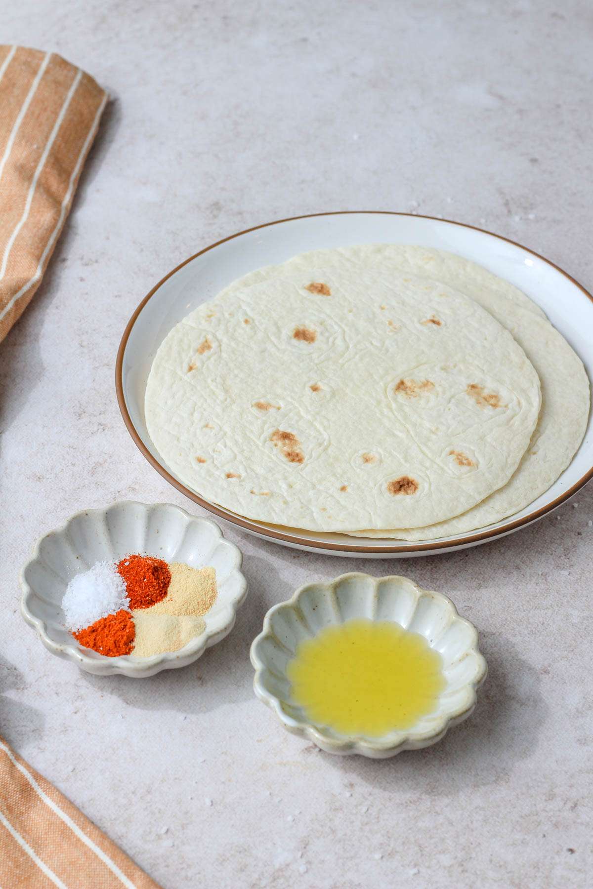 Ingredients for seasoned air fryer flour tortilla chips on a tan counter.