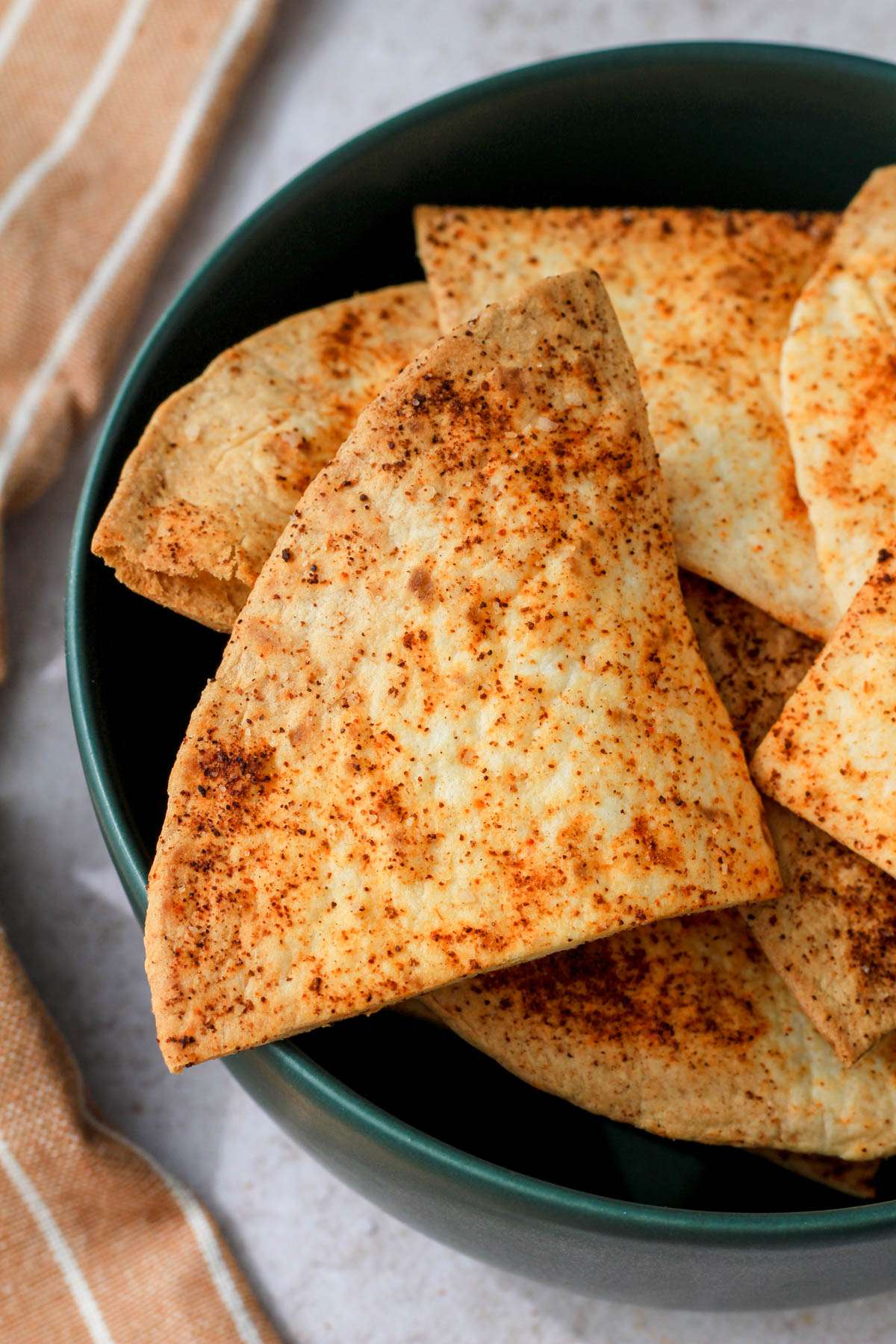 A green bowl filled with vegan flour tortilla chips made in the air fryer.