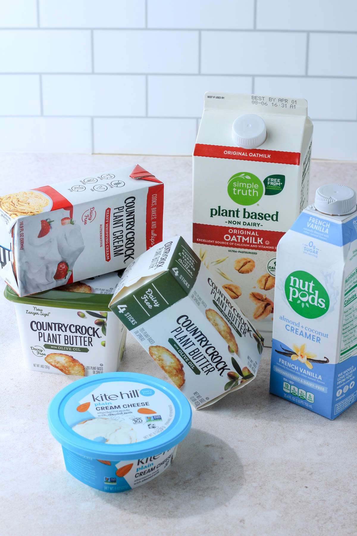 Stacks of milk, butter, cream cheese, and creamer on a tan counter.