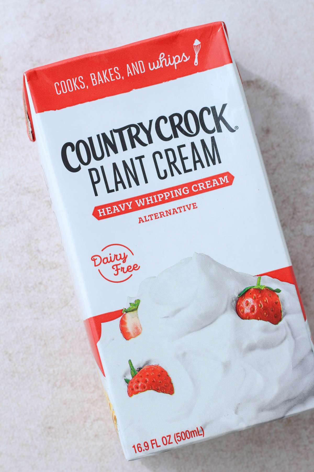 A red and white carton of plant cream on a tan counter.