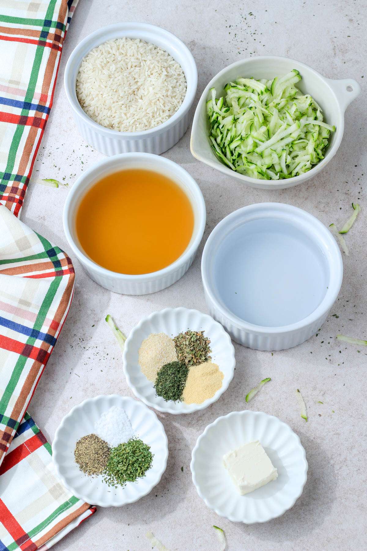 Ingredients for vegan seasoned zucchini rice on a cream counter.