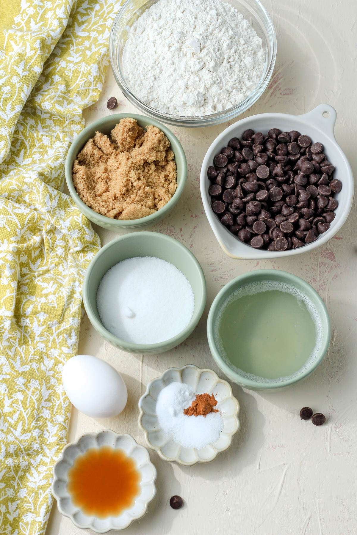 Ingredients for coconut oil chocolate chip cookies on a cream counter.