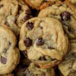 A close up of a dairy-free coconut oil chocolate chip cookie topped with flaky sea salt.