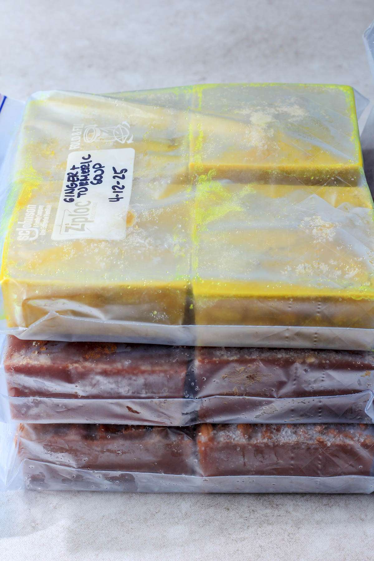 A stack of three freezer safe bags with cubes of frozen food for postpartum.