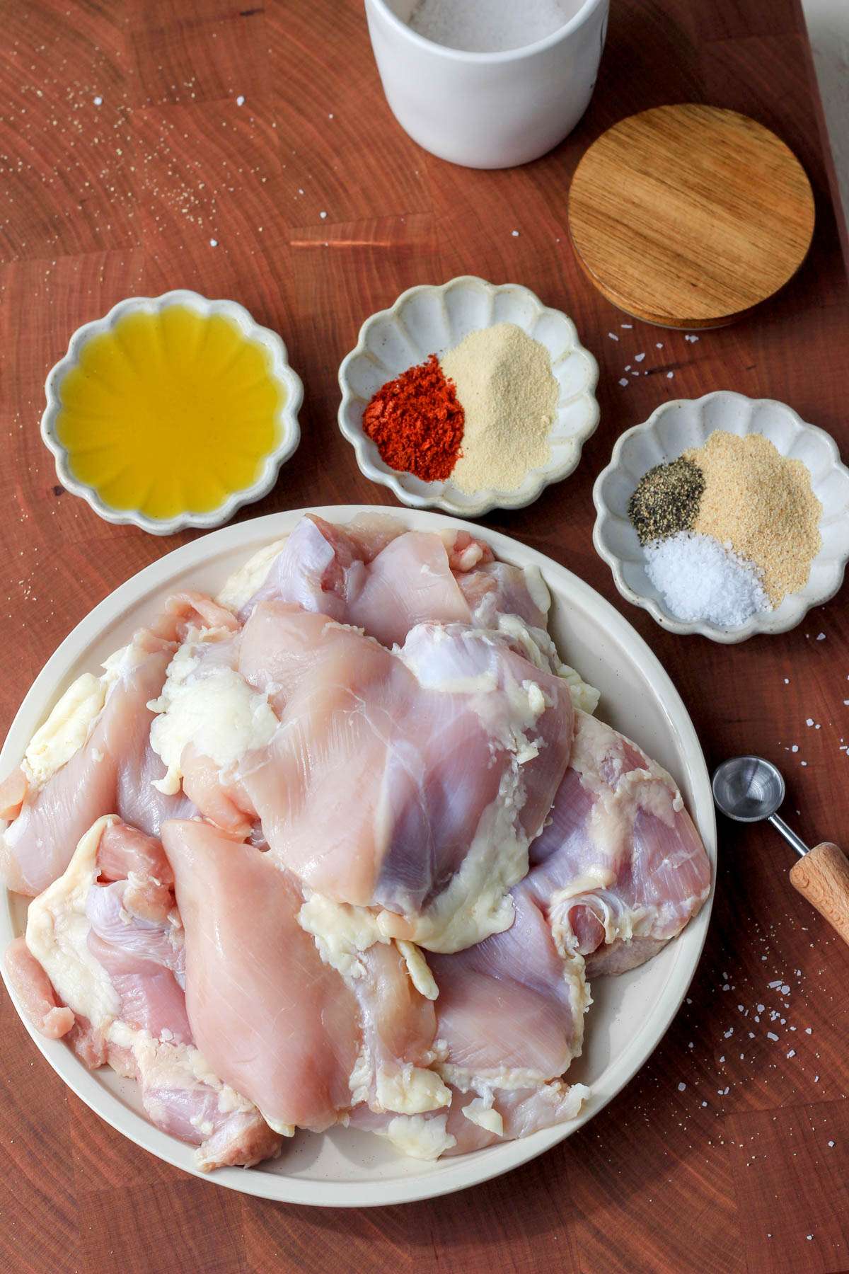 Ingredients for grill pan chicken thighs on a wooden cutting board.
