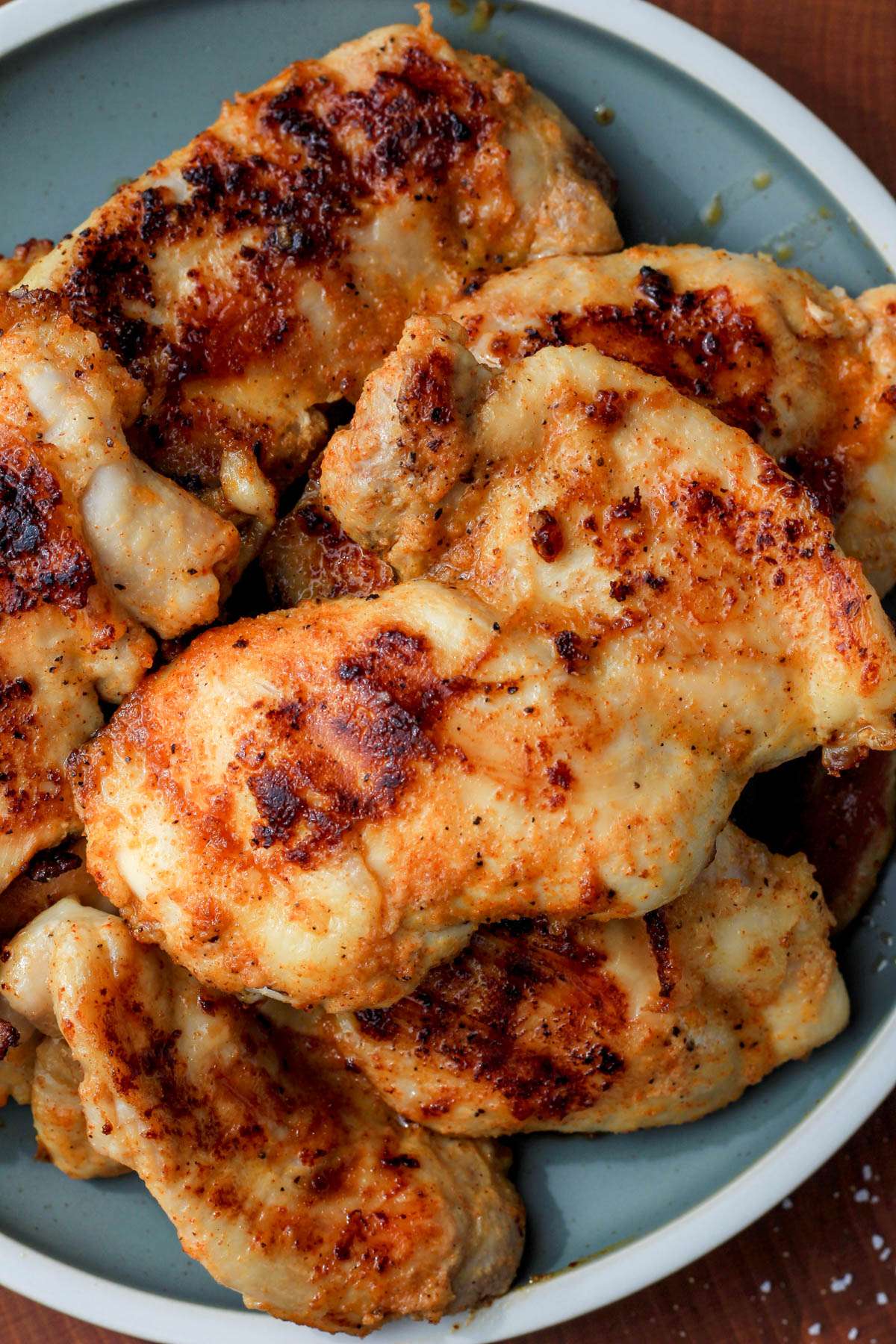 A green plate with a white rim topped with grill pan chicken thighs.