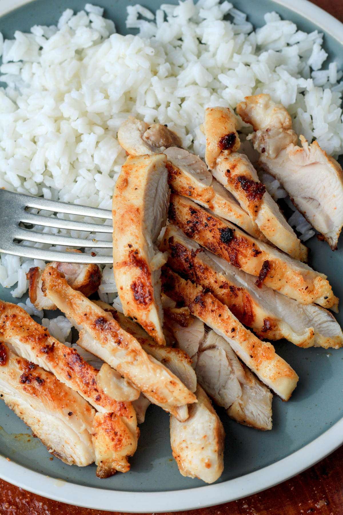 A green plate with rice and grill pan cooked chicken.