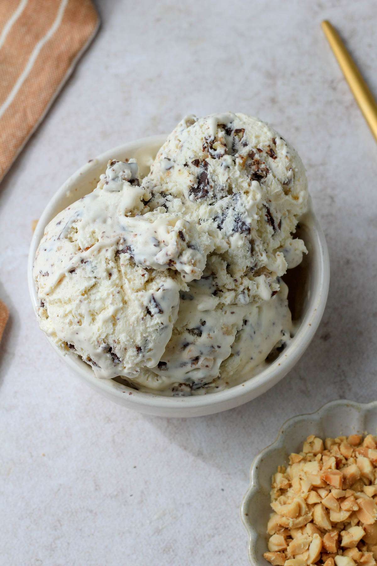 A white bowl of drumstick ice cream with a small dish of peanuts to the bottom right.