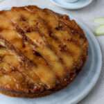 A close up of a marble cake stand with a vegan cinnamon apple upside down cake on the stand.
