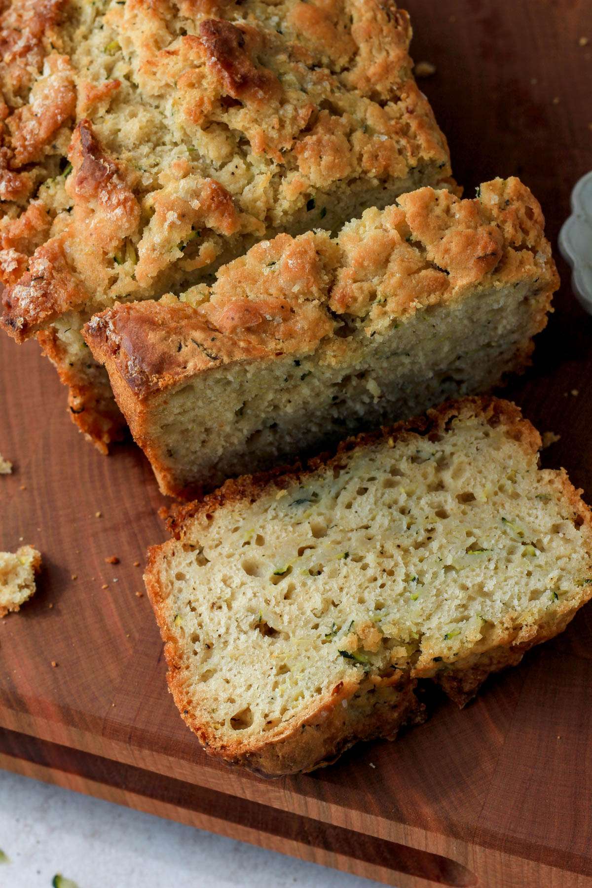 A wooden cutting board with slices of zucchini beer bread cut on the board.