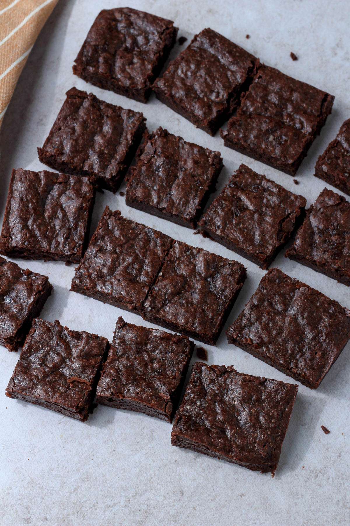 A parchment paper with cut squares of dairy-free brownies.