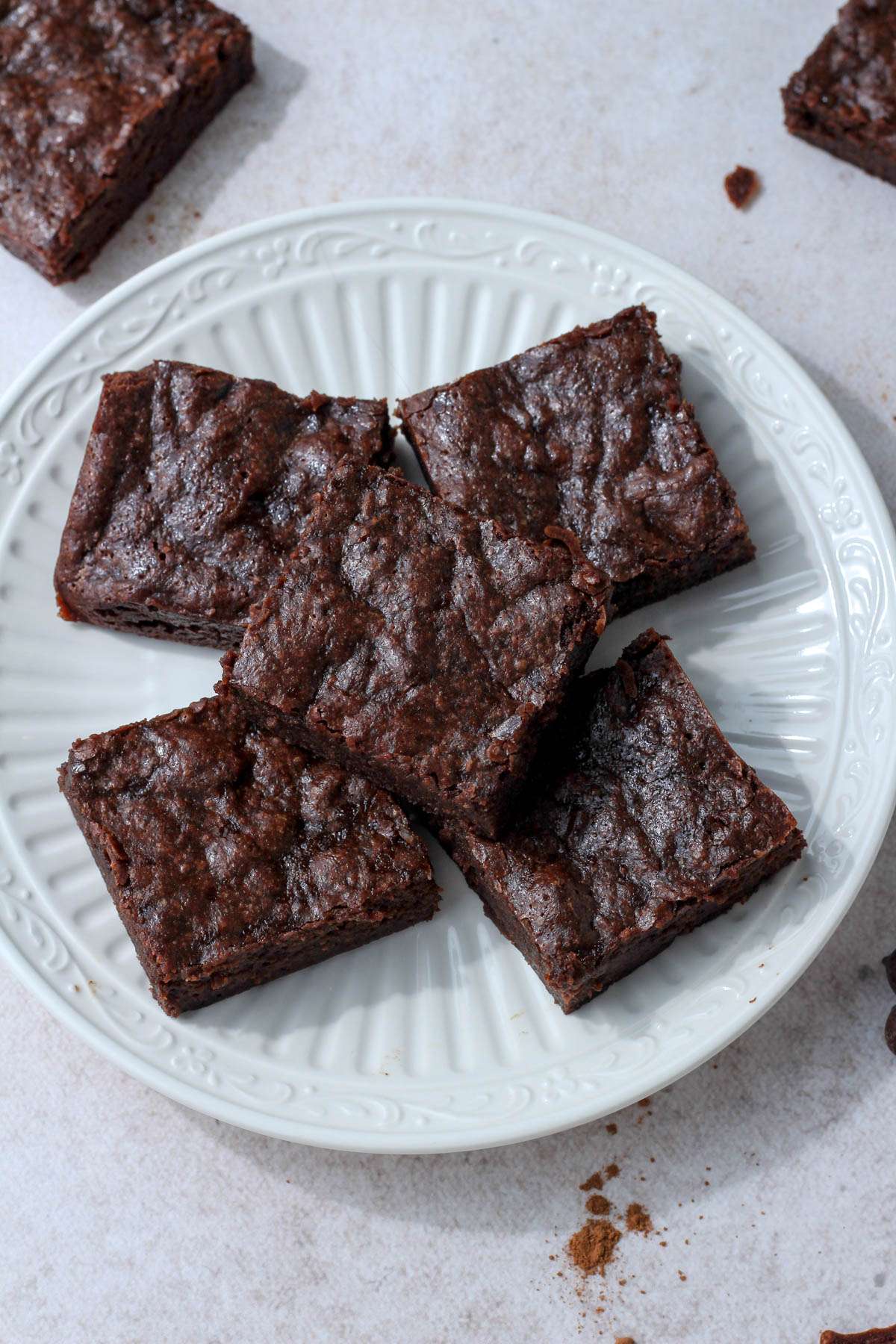 A white plate with dairy-free chocolate brownies with banana and coconut oil.