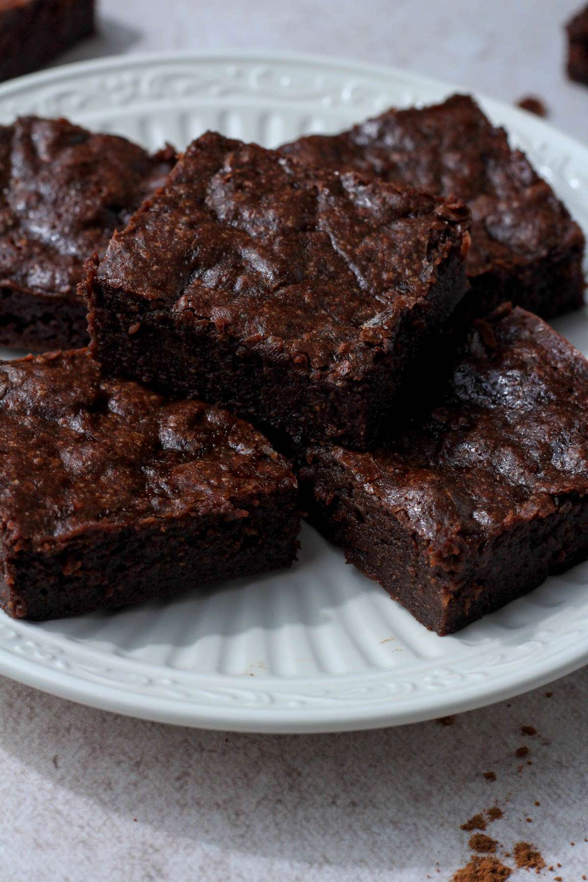 Dairy-free banana brownies on a white plate stacked in a small circle.