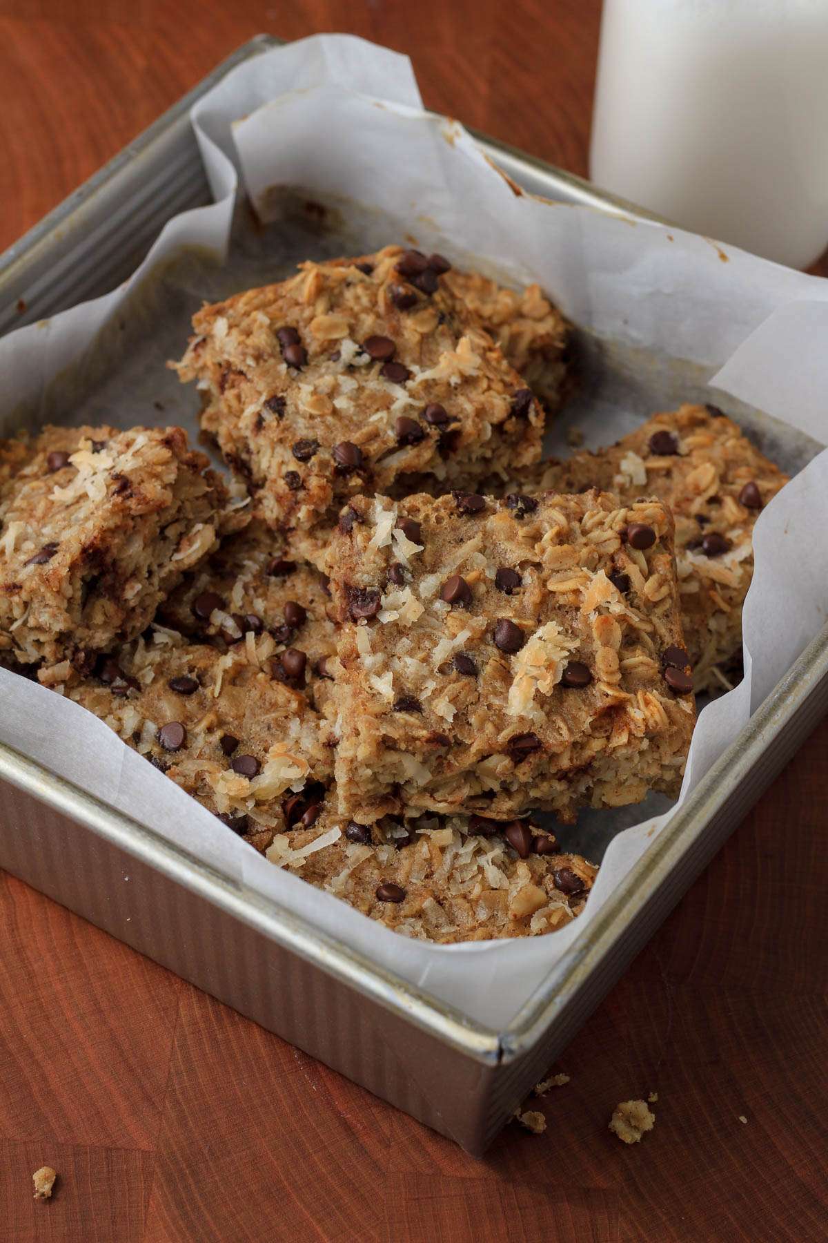 A silver baking dish lined with parchment paper and filled with sliced pieces of almond joy baked oatmeal bars.