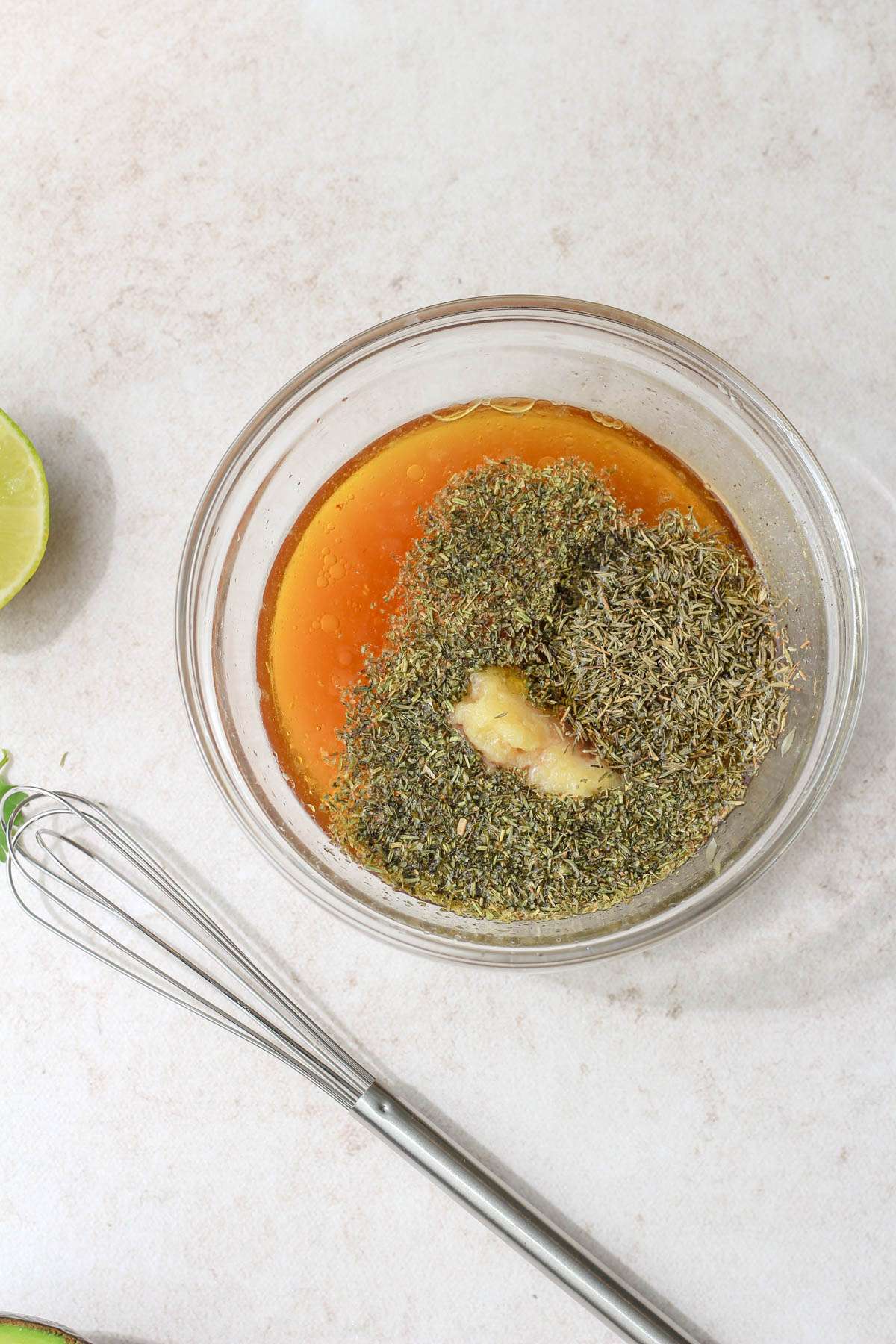 A small glass mixing bowl with ingredients for the dressing before mixing.