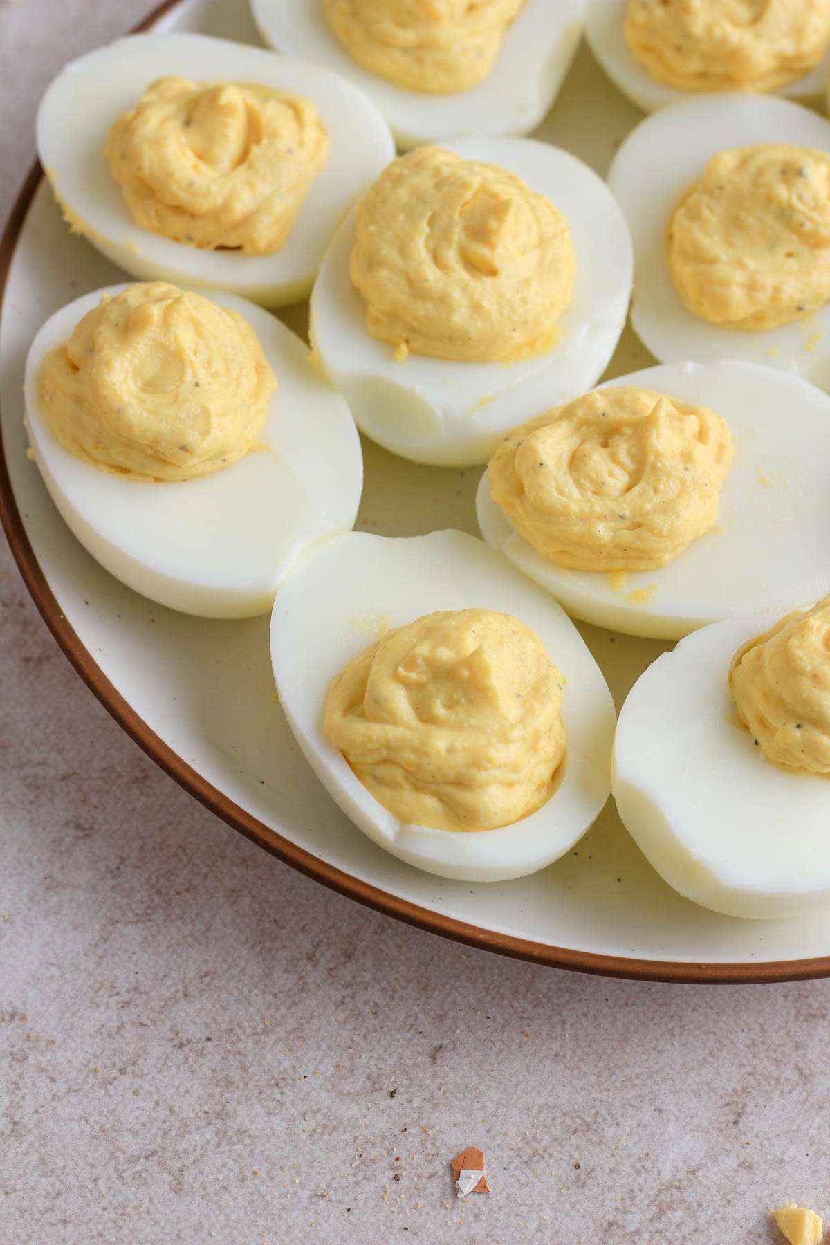 A brown and white plate topped with classic deviled eggs on a light brown counter.