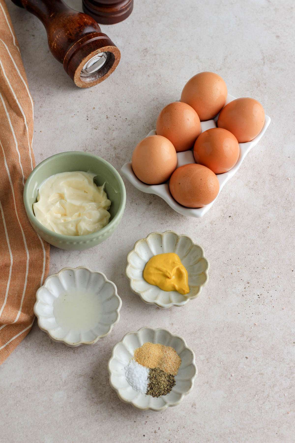 Ingredients for making classic deviled eggs on a light brown counter.
