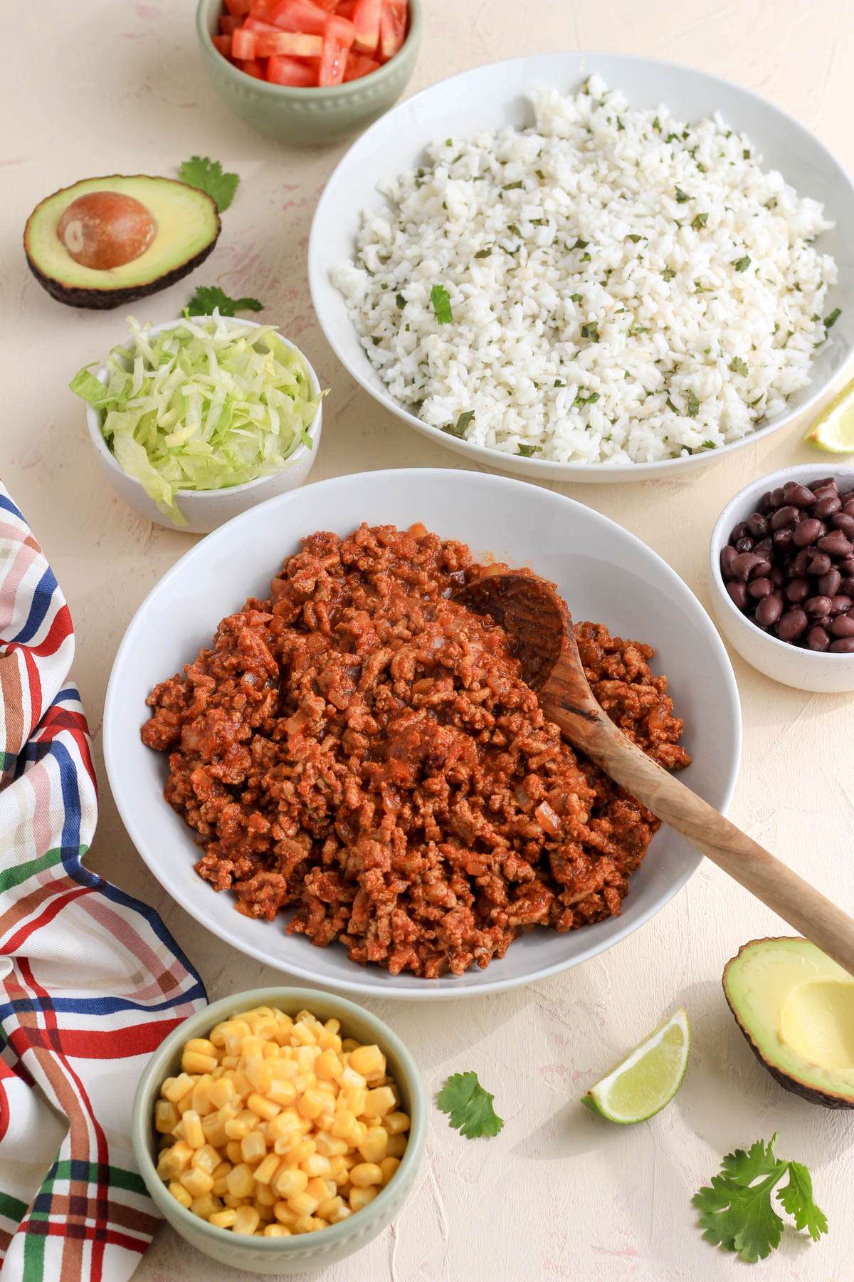 A cream and pink counter with bowls of ingredients to make taco lunch bowls.