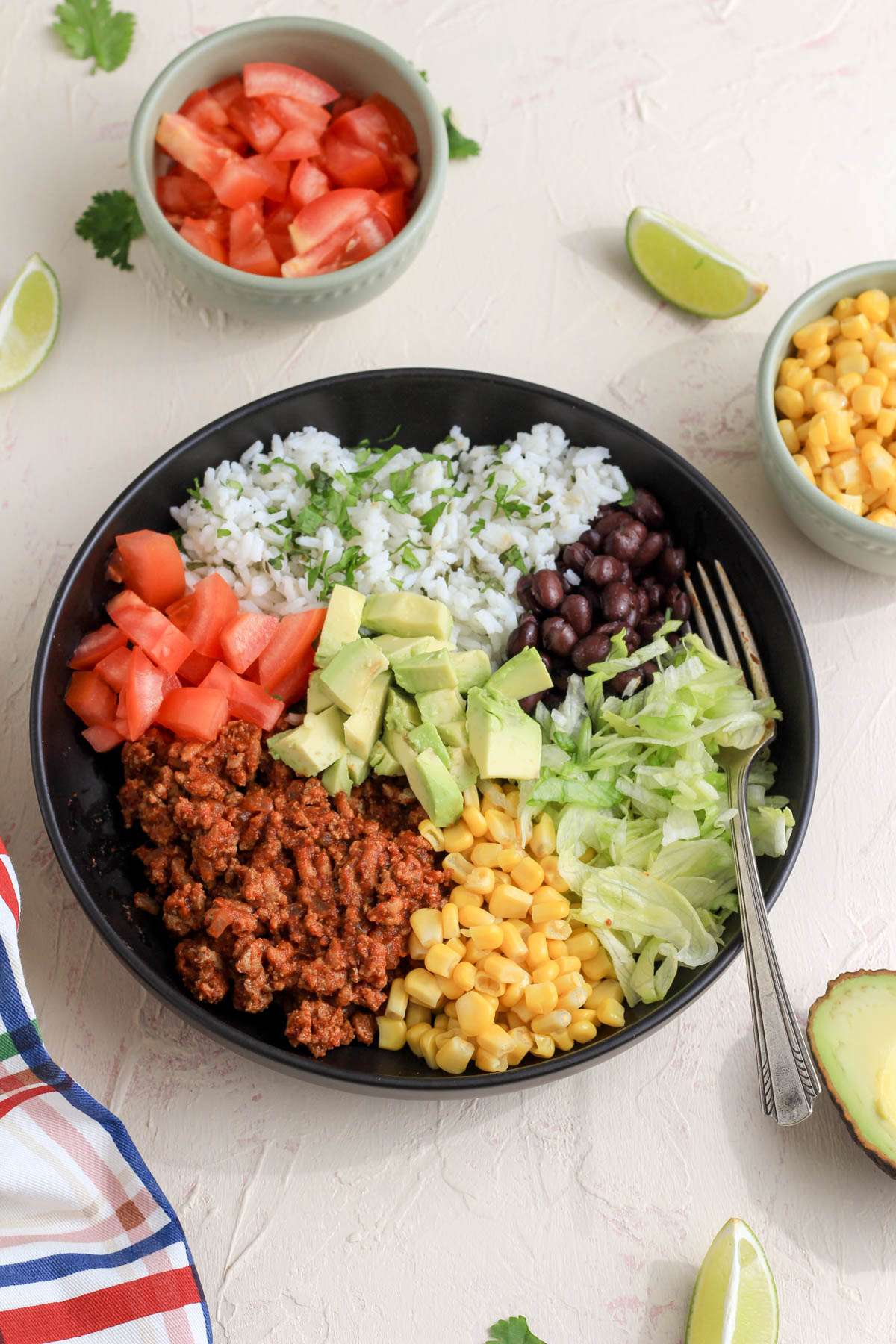 A black bowl on a cream and pink counter with a taco lunch bowl and a silver fork on the right side of the bowl.