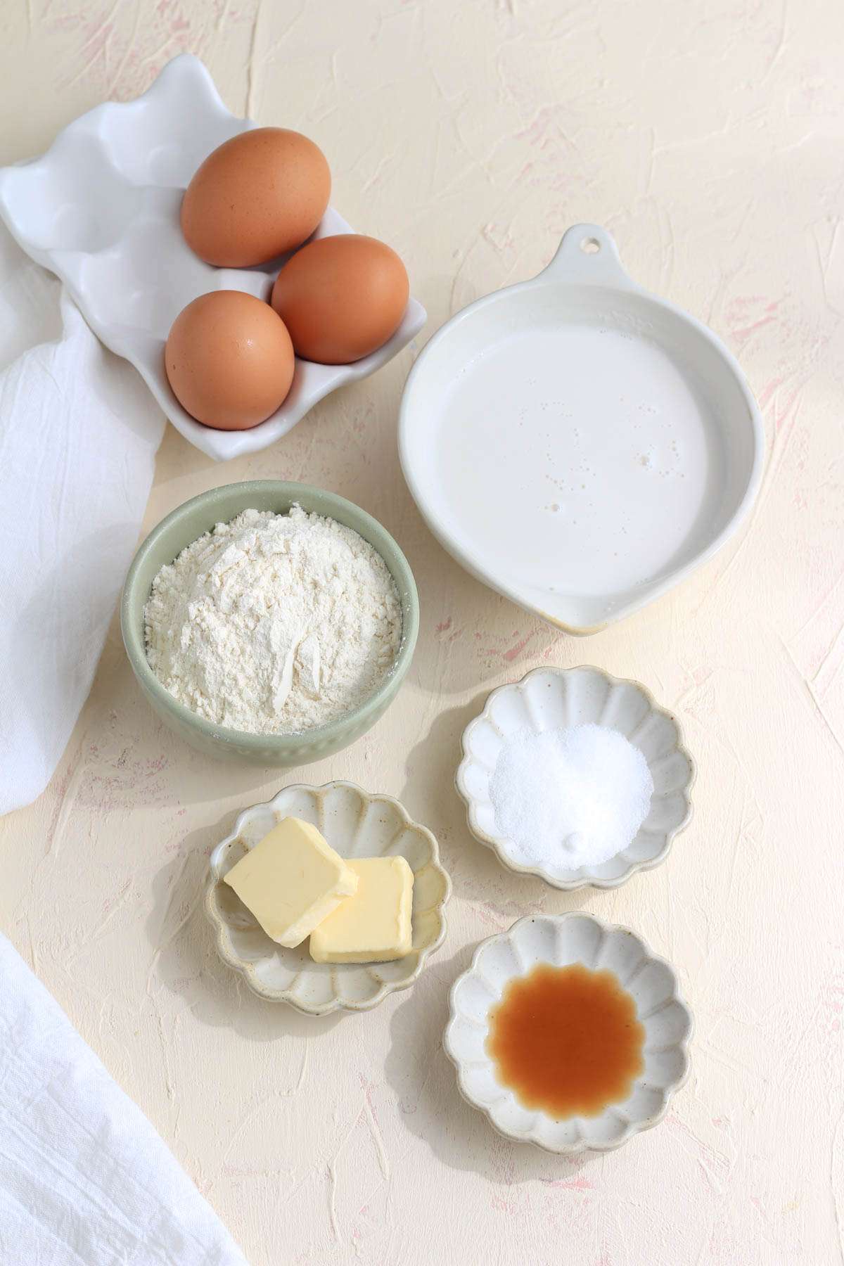 Ingredients for a dutch baby pancake on a cream and pink counter.