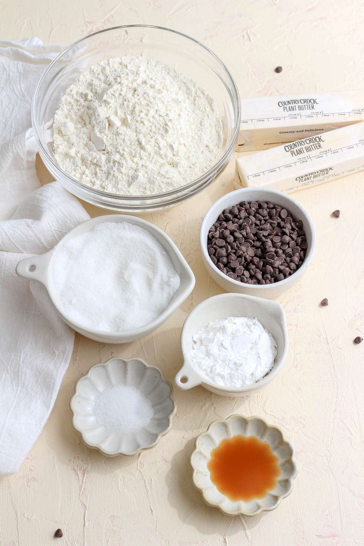 Ingredients for vegan chocolate chip shortbread cookies on a cream counter.