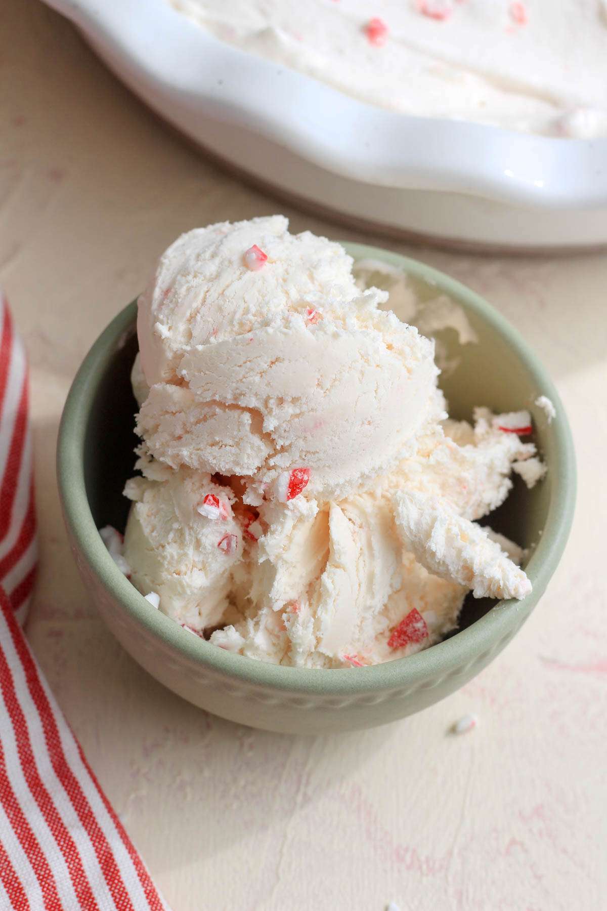 A small green bowl filled with vegan peppermint ice cream on a cream counter.