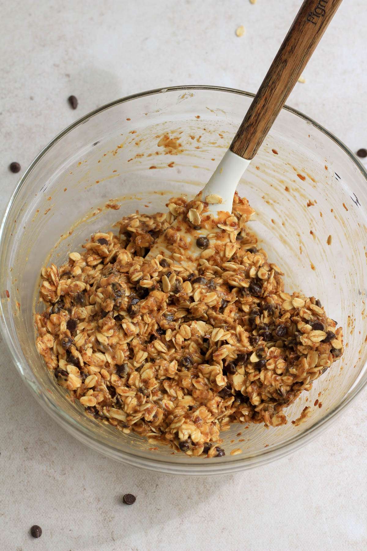 A glass mixing bowl with a rubber spatula after mixing the ingredients for chocolate peanut butter lactation bites.