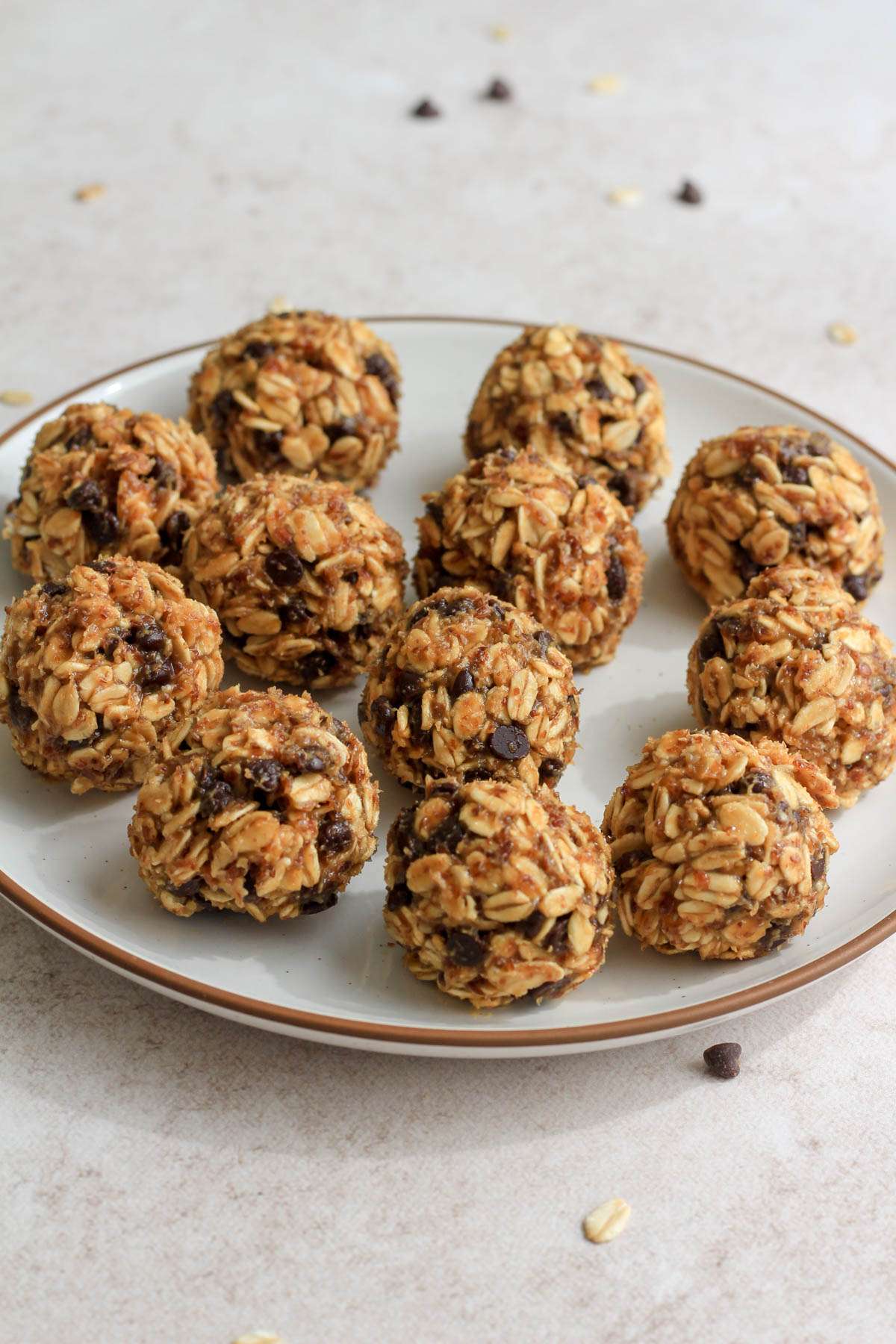 From the side, balls of peanut butter chocolate chip lactation bites on a white plate with a brown rim.