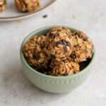 A close up of a small green bowl filled with chocolate chip peanut butter lactation bites.