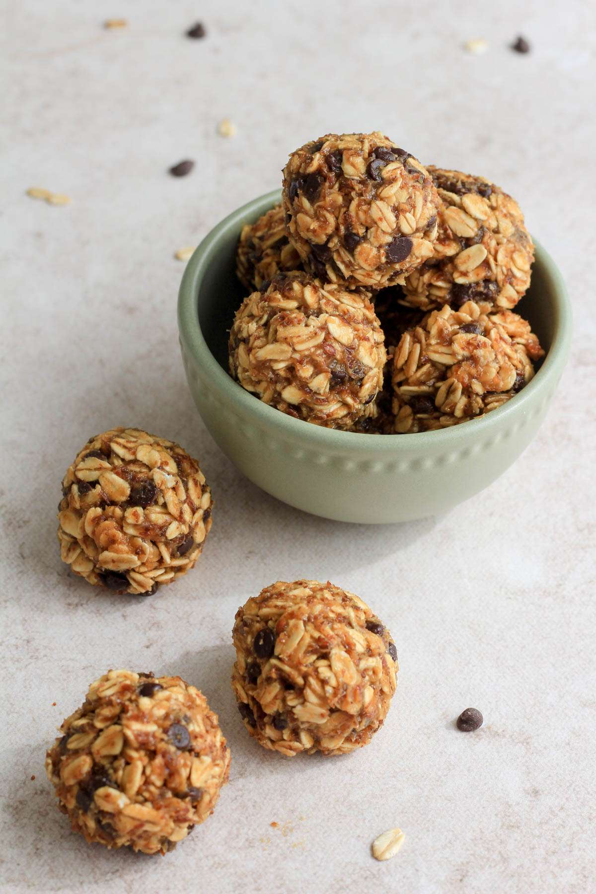 A small green bowl on a tan counter filled with lactation bites with three bite in front of the bowl to the left.